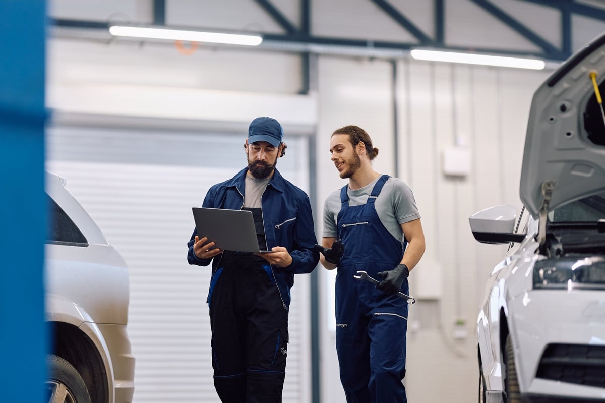 Mechanics using laptop in auto repair shop